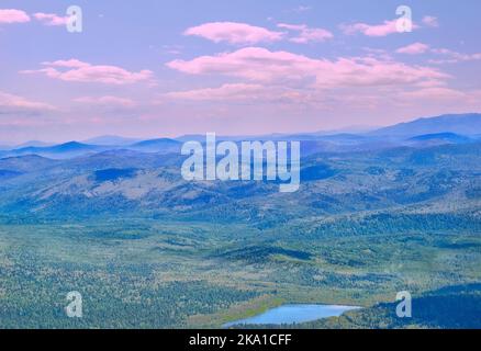 Vallée de montagne avec lac bleu parmi les forêts profondes dans la lumière rose du matin - paysage idyllique d'été. Pics de montagne sous la brume bleue du matin et la cl rose Banque D'Images