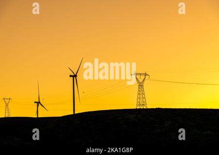 Plusieurs éoliennes se tenant sur une colline au coucher du soleil et générant de l'électricité Banque D'Images