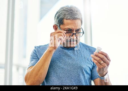 Cela ressemble à celui-ci. Un beau homme âgé lisant une bouteille de médicament d'ordonnance. Banque D'Images