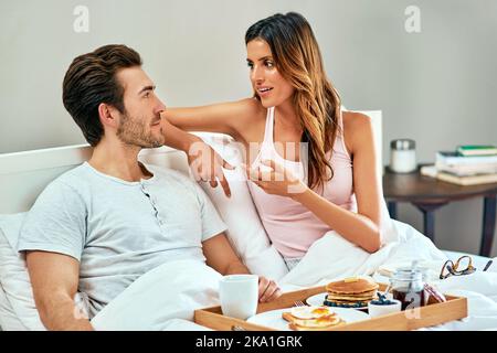 Un petit déjeuner au lit. Un jeune couple heureux qui prend son petit déjeuner au lit à la maison. Banque D'Images