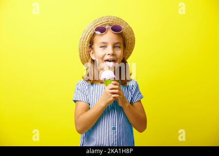 Petite fille gaie avec de la crème glacée sur fond jaune isolé. Banque D'Images