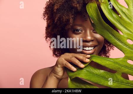 Une fille afro-américaine sort de la feuille de Monstera. Banque D'Images