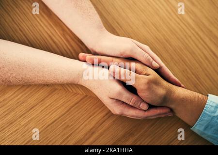 Vous êtes maintenant dans un espace sûr. Un homme et une femme tenant les mains confortablement sur une table. Banque D'Images