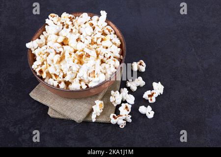 Pop-corn dans un bol de nourriture sur fond de pierre noire Banque D'Images