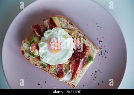 Vue rapprochée des toasts d'avocat avec jambon et œuf servis sur une assiette. Banque D'Images