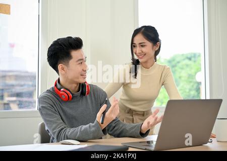 Des jeunes hommes et femmes de bureau asiatiques joyeux et talentueux remue-méninges, partagent des idées créatives et travaillent ensemble au bureau. Banque D'Images