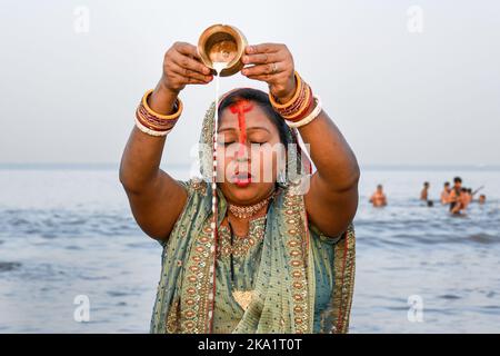 Mumbai, Inde. 31st octobre 2022. Une femme hindouiste verse du lait dans une casserole de cuivre dans l'eau alors qu'elle prie le soleil levant à l'occasion de Chhath Puja à Juhu Beach, Mumbai. Les dévotés, surtout des États du Nord de l'Inde prient au Dieu du soleil (le coucher et le lever du soleil) le remerciant d'avoir donné la vie sur la terre. Les dévotés se trempent dans les plans d'eau et restent rapides à l'occasion. Crédit : SOPA Images Limited/Alamy Live News Banque D'Images