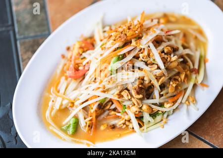 Salade de papaye thaï épicée ou Som Tum Thai, vue d'en haut, image rapprochée, lumière naturelle et chaude. Banque D'Images