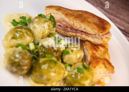 Recette pour des filets de poulet faits maison de style cordon bleu avec choux de Bruxelles Banque D'Images