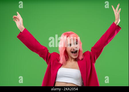 Une jeune fille extravagante excitée qui pose pour l'appareil photo dans un studio Banque D'Images