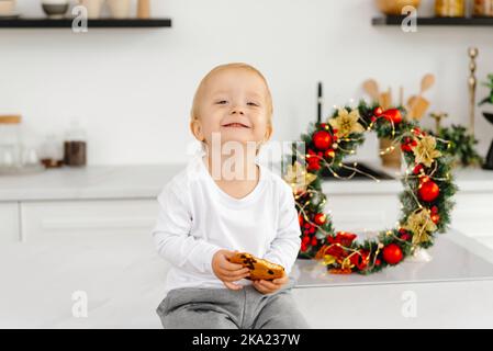 L'enfant s'assoit et sourit pour la caméra. Un enfant heureux à Noël. Bonne famille et harmonie sociale. Banque D'Images