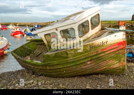 Un vieux et décrépi petit bateau de pêche appelé Jennifer attaché et hors de l'eau dans Paddy's Hole, un petit refuge sur la rive sud du RI Banque D'Images