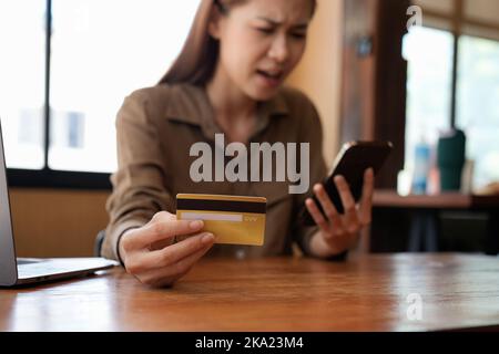 Mécontent jeune asiatique acheteur ont des problèmes d'achat en ligne sur Internet sur smartphone avec carte de crédit. Une femme frustrée en colère confondue avec le compte Banque D'Images