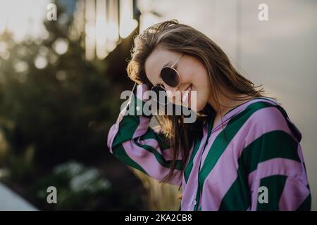 Portrait d'une belle jeune femme en plein air en ville, au coucher du soleil. Banque D'Images