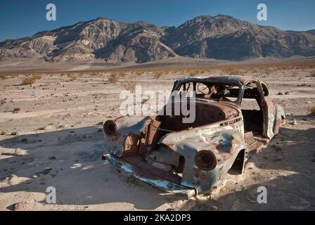Épave de voiture ancienne, criblée de balles, four Mine Road dans la vallée de Panamint, Inyo Mountains à distance, désert de Mojave, parc national de la vallée de la mort, Californie Banque D'Images