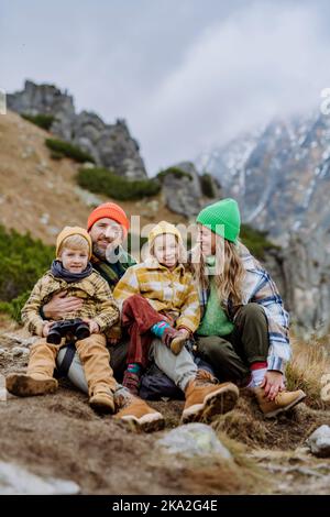 Bonne famille assise et repos, pendant la randonnée ensemble dans les montagnes d'automne. Banque D'Images