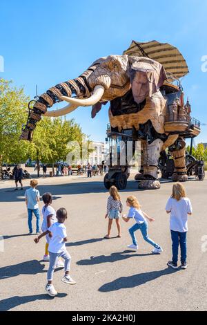 La marionnette géante du grand éléphant, qui fait partie des machines de l'attraction touristique de l'île de Nantes, se promène lentement au milieu d'enfants enthousiastes par une journée ensoleillée. Banque D'Images