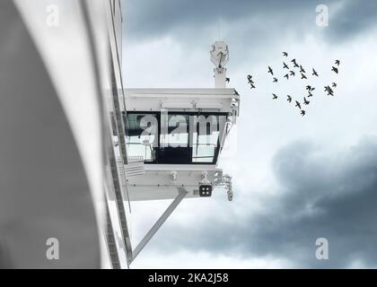 Grand pont de capitaine de bateau de croisière vu du côté avec un troupeau d'oiseaux de mer volant au-dessus dans un ciel spectaculaire. Banque D'Images