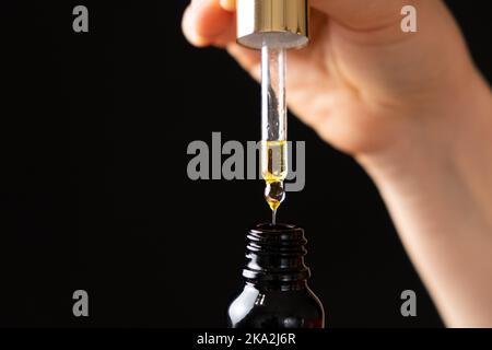 Huile naturelle pour le soin des cils, sourcils, peau du visage goutte dans un pot en verre de pipette Banque D'Images