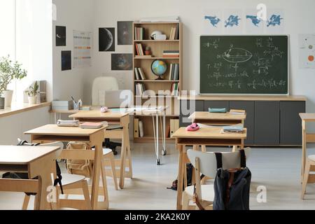 Salle de classe vide d'algèbre ou sujet de physique avec des formules écrites sur tableau noir et des rangées de bureaux dans l'école secondaire moderne Banque D'Images