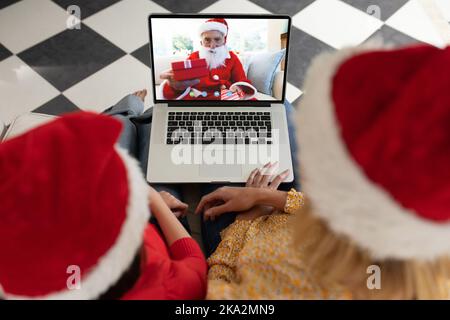 Divers couple ayant un appel vidéo de noël avec un homme caucasien portant le costume du père noël Banque D'Images