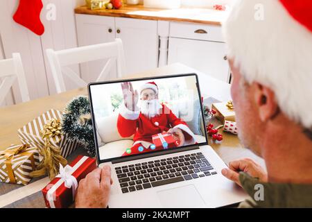 Homme caucasien âgé ayant un appel vidéo de noël avec un homme caucasien portant le costume du père noël Banque D'Images