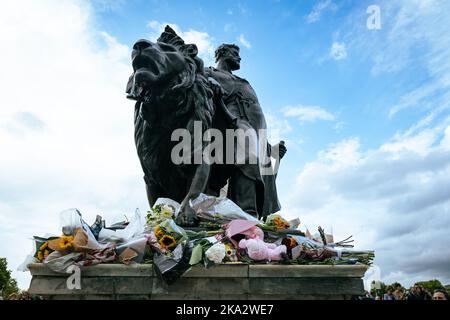 Fleurs laissées en hommage sous une statue d'un lion à l'extérieur de Buckingham Palace, Londres, Royaume-Uni. Banque D'Images