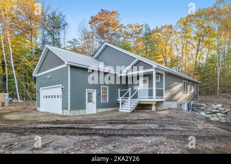 Une maison avec un garage et un escalier pour la porte d'entrée construite dans une forêt entourée de feuillage d'automne Banque D'Images
