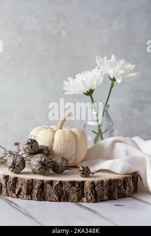 Citrouille BabyBoo Ghost sur bloc de bois avec graines de nigelle, serviette en lin, chrysanthèmes blancs sur fond clair. Espace pour la copie Banque D'Images