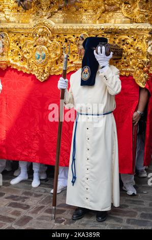 Les personnes portant des vêtements traditionnels aux couleurs vives prennent part à une parade de Pâques, portant un trône pendant la semaine Sainte ou le Santa de sémana à Cadix, Espagne Banque D'Images