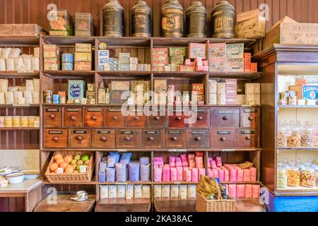 Étagères et tiroirs dans une épicerie traditionnelle irlandaise boutique 19th Century 1800s avec des articles ménagers comme le savon, les produits de blanchisserie, les herbes, le thé et la farine. Banque D'Images