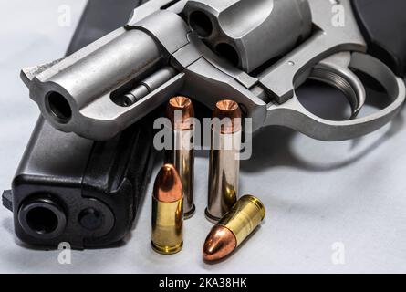 Deux pistolets, un pistolet noir 9mm et un Magnum en acier inoxydable 357 avec deux balles pour chacun d'eux sur fond blanc Banque D'Images