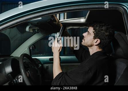 Mécanicien utilisant la lampe à l'intérieur de la voiture Banque D'Images