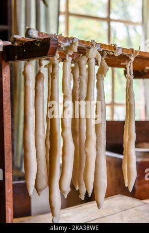 Bougies faites à la main séchant sur un rack à l'intérieur d'une maison. Banque D'Images