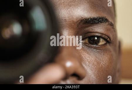 Photographe noir regardant l'appareil photo à travers l'objectif Banque D'Images