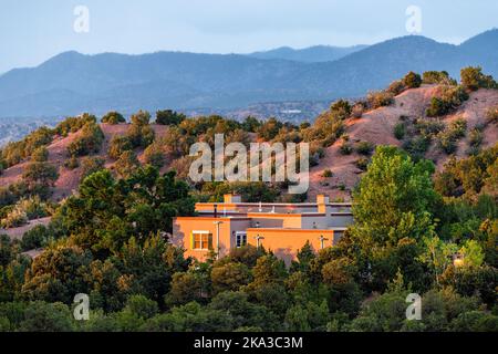 Coucher de soleil à Santa Fe, montagnes du Nouveau-Mexique dans le quartier de la communauté de Tesuque avec la lumière du soleil sur la maison avec plantes vertes et arbustes et ciel bleu foncé Banque D'Images