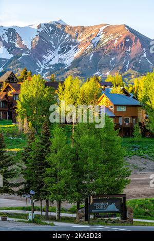 Station de ski de Mount Crested Butte village, Colorado en été avec lever de soleil nuageux matin et maisons sur des collines avec arbres verts et panneau de rue principal Banque D'Images