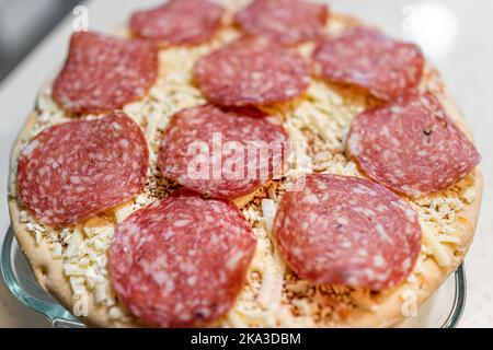 Macro gros plan de crues non cuites prendre et cuire au four la tarte à pizza au fromage mozzarella poivré surgelée sur un plateau prêt à cuire Banque D'Images