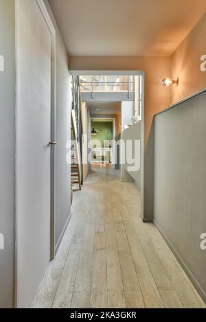 Couloir lumineux de l'appartement moderne menant à la porte ouverte de la chambre avec bureau Banque D'Images