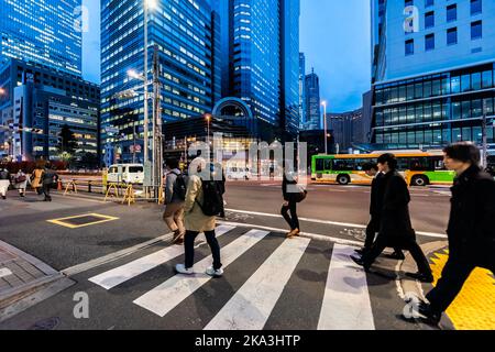 Shinjuku, Japon - 1 avril 2019: Gens, hommes d'affaires traversant la rue transversale dans le centre-ville de Tokyo avec des bâtiments modernes pendant l'heure bleue la nuit Banque D'Images