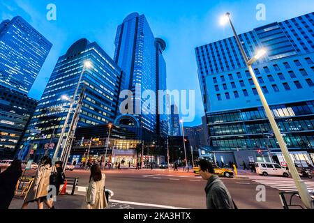Shinjuku, Japon - 1 avril 2019: Gens, femmes d'affaires traversant la rue transversale dans le centre-ville de Tokyo avec des bâtiments modernes à l'heure bleue nuit Banque D'Images
