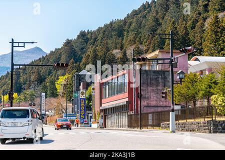 Nikko, Japon - 4 avril 2019: Montagne dans la ville-préfecture de Tochigi, petite ville au ciel bleu au printemps sur la rue avec circulation de voitures par le parking Banque D'Images