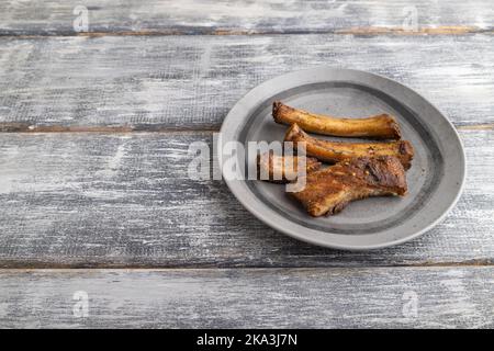 côtes de porc sur une assiette en bois sur fond de bois gris. Vue latérale, gros plan, espace de copie. Banque D'Images