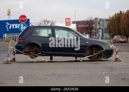 Pologne, Poznan - 30 octobre 2022: Une voiture sans roues garée dans un parking de magasin. Les voleurs ont remplacé les roues par des pierres. Vandalisme. Banque D'Images