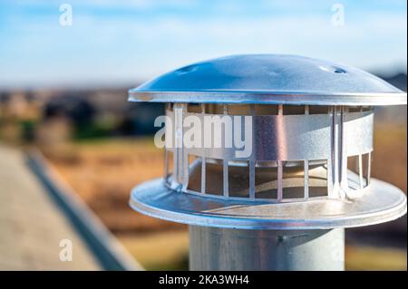 Vue latérale d'une cheminée d'échappement en métal galvanisé sur un toit en asphalte avec un capuchon de pluie Banque D'Images