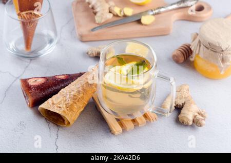 Thé chaud au citron et à la menthe dans une tasse de verre avec rouleau de cuir de fruits secs. Boisson chaude d'automne ou d'hiver. Le concept de santé. Banque D'Images