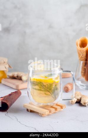 Thé chaud au citron et à la menthe dans une tasse de verre avec rouleau de cuir de fruits secs. Boisson chaude d'automne ou d'hiver. Le concept de santé. Banque D'Images