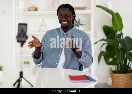 Jeune homme afro-américain souriant enregistrement vidéo Vlog avec smartphone à la maison Banque D'Images