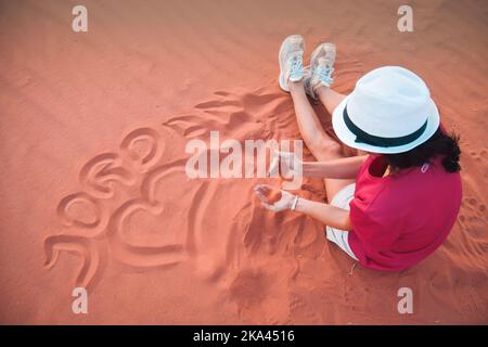 Belle jeune femme jouant avec du sable sur une dune de sable du désert de Wadi Rum, également appelé Wally de la lune, de Jordanie. Vacances en Jordanie. Banque D'Images