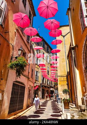 Grasse, France - 6 août 2022 : maisons de tenement historiques et rues étroites décorées de parasols roses de la vieille ville de la ville de parfumerie Banque D'Images